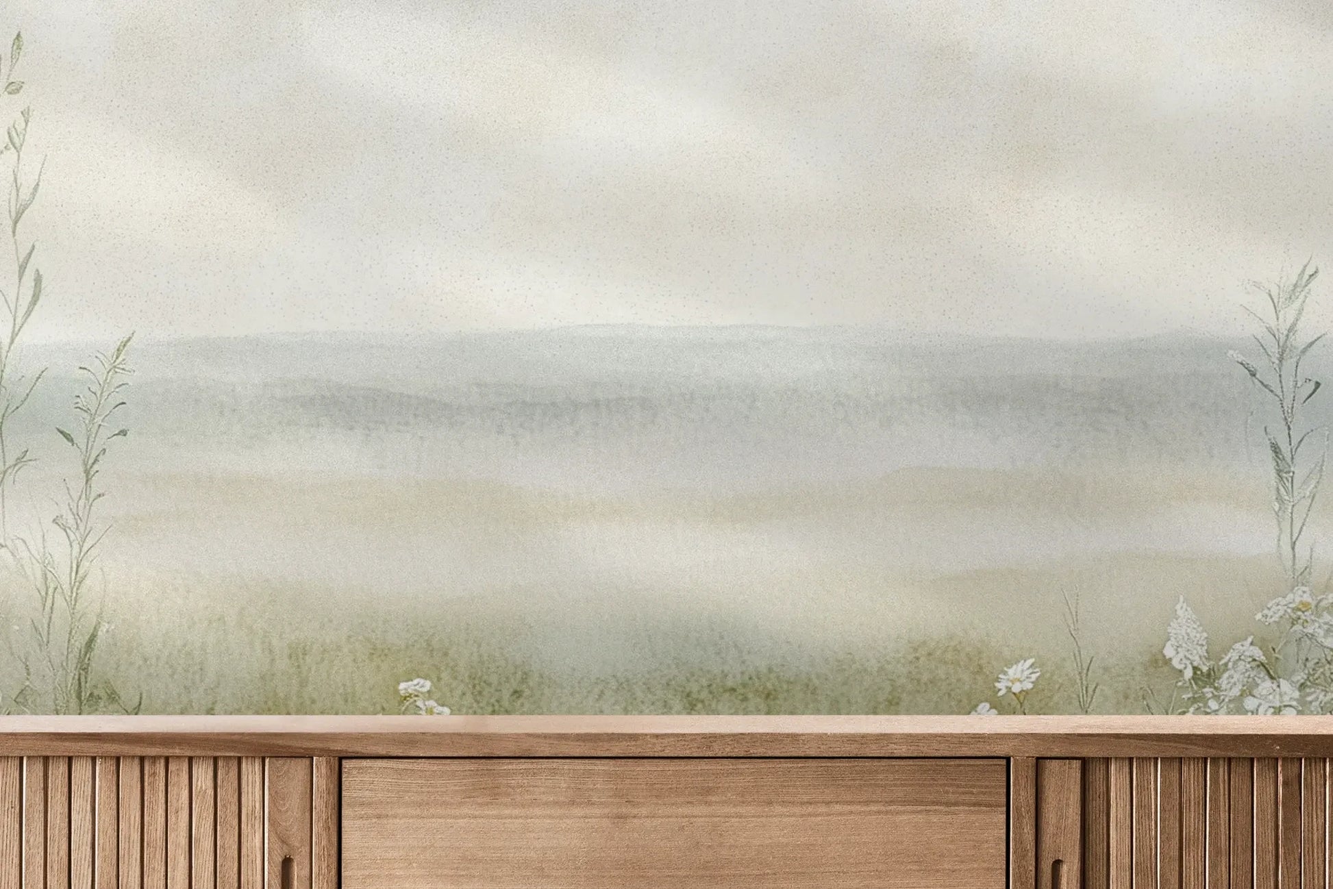 Fototapeta DAWN'S EMBRACE - tapeta z mglistą łąką i kwiatami pokazana w aranżacji wnętrza z akcentem na ścianie.