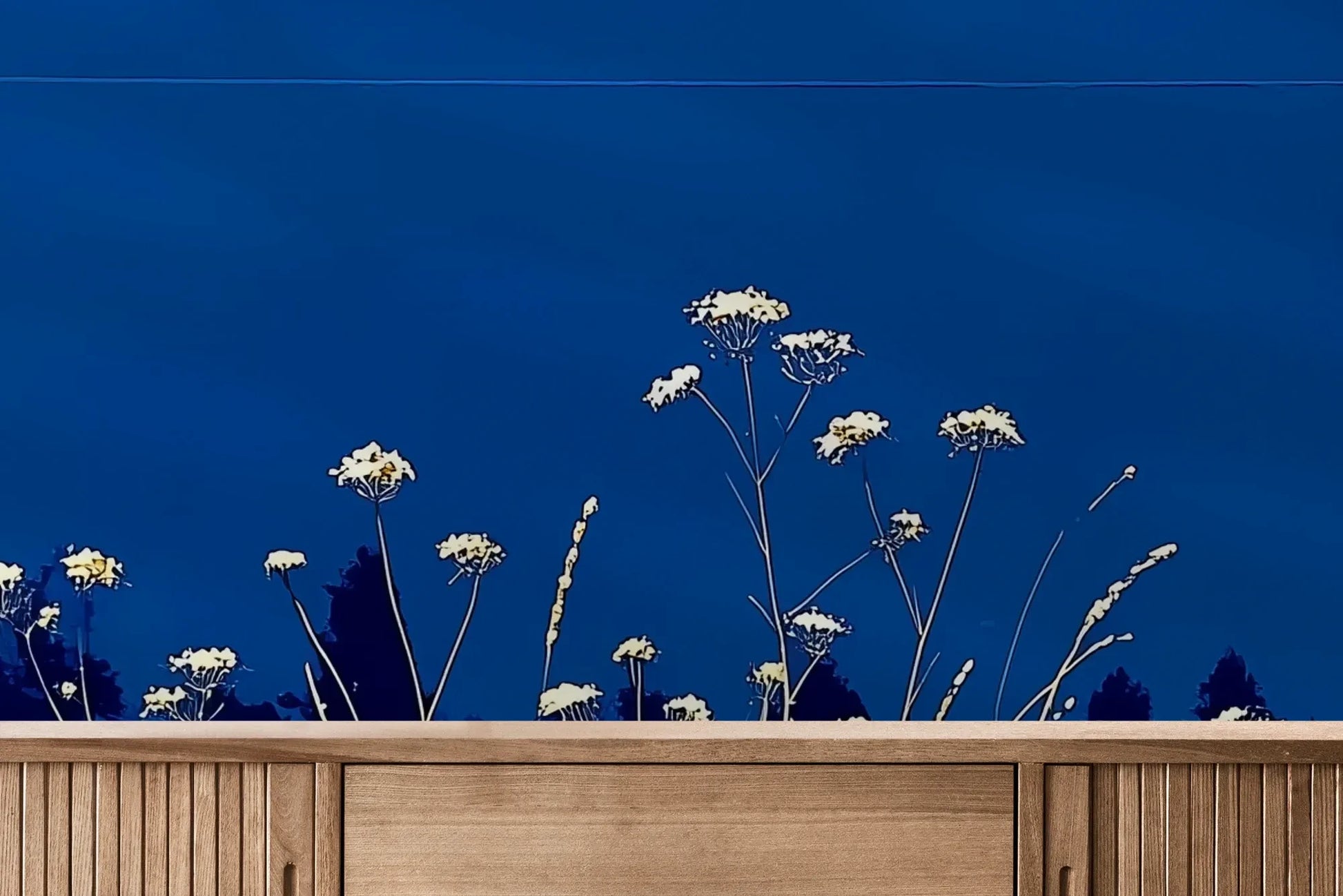 Fototapeta SAPPHIRE HORIZON - tapeta z lazurową łąką i białymi kwiatami pokazana w aranżacji wnętrza z akcentem na ścianie.
