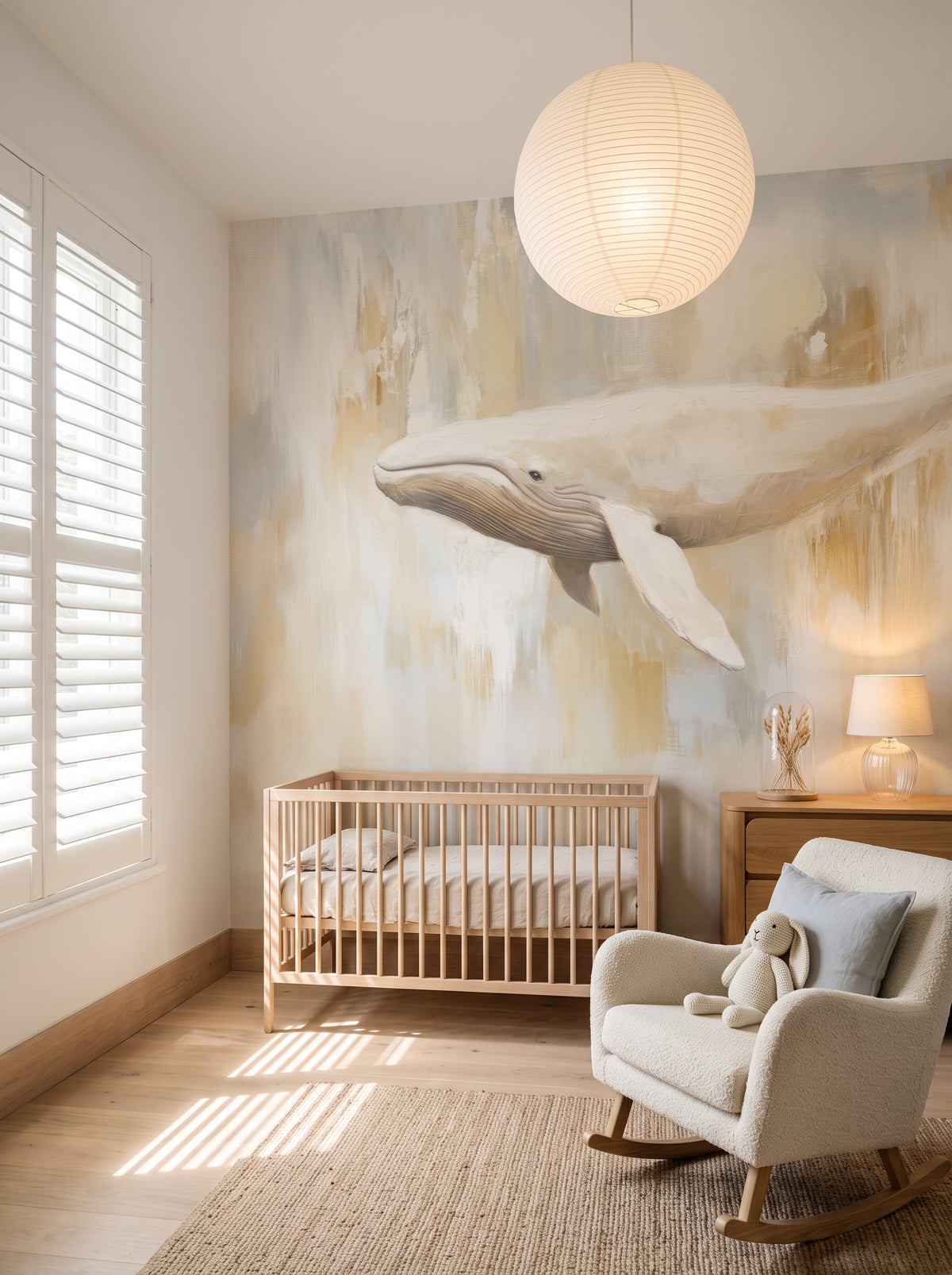 MILK AND HONEY in a baby’s room setting: cream whale on a light background above a wooden cot, with a rocking chair beside it