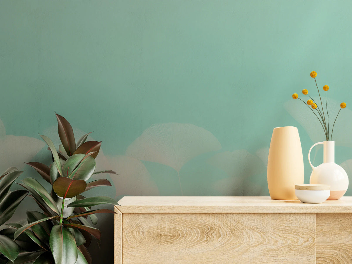 MINT SORBET de près – éventails embrumés de feuilles sur fond menthe, juste au-dessus du plateau d'une commode claire en bois