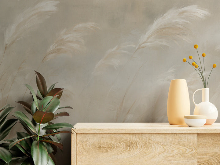 PAMPERO de près : plumeaux picturaux et fond toilé au-dessus d'une commode en bois clair ornée de vases