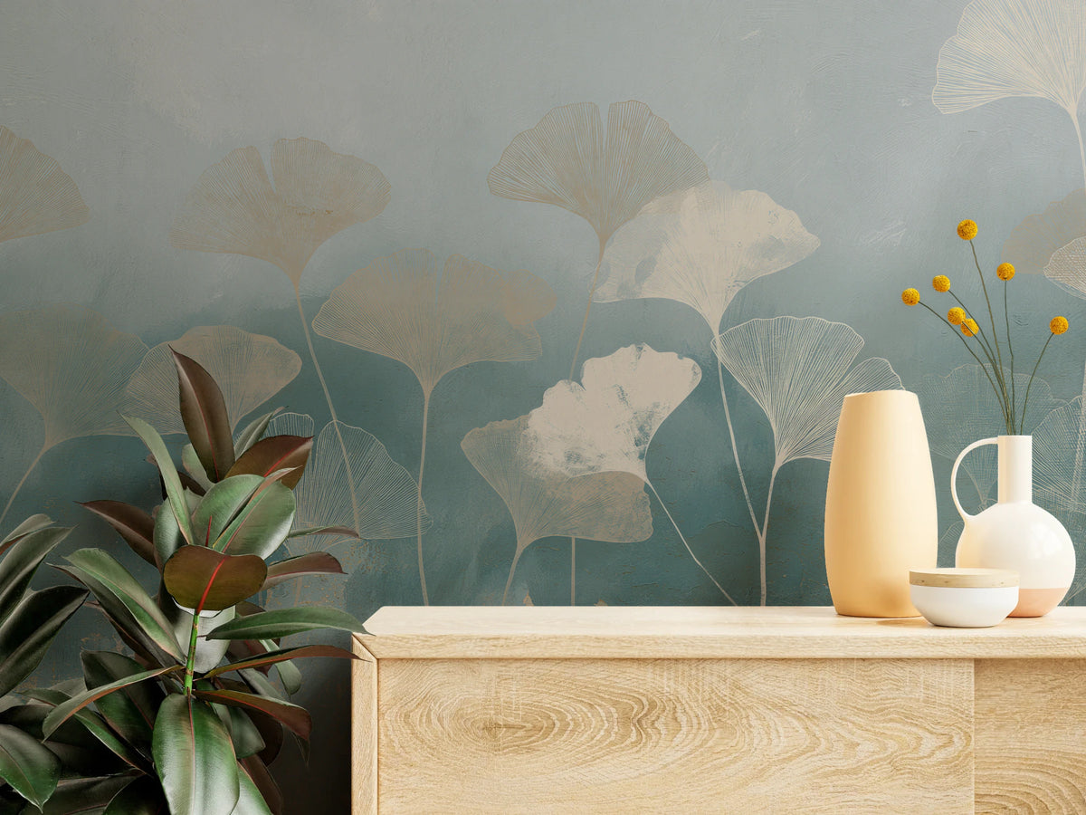 TALC AND TEAL de cerca: hojas de ginkgo sobre fondo azul mar detrás de una cómoda clara con jarrones y un ficus
