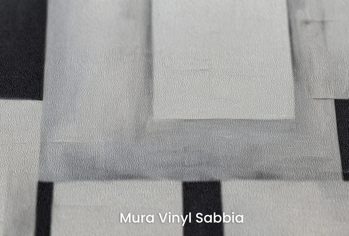 Zbliżenie na artystyczną fototapetę o nazwie Monochrome Blocks na podłożu Mura Vinyl Sabbia struktura grubego ziarna piasku.